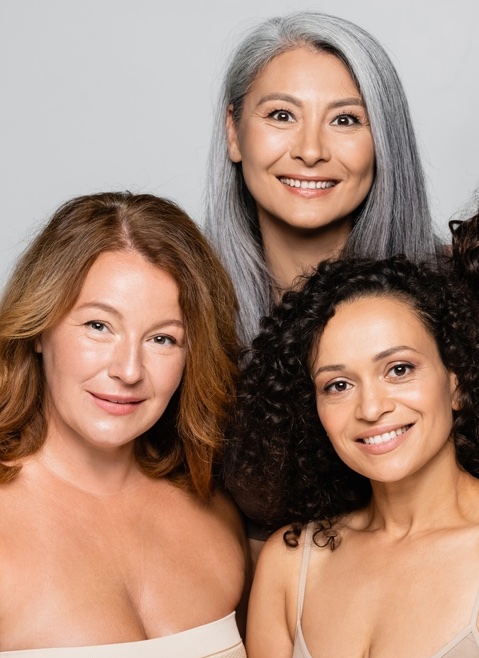 Drei Frauen mittleren Alters mit schöner Haut lächeln in die Kamera