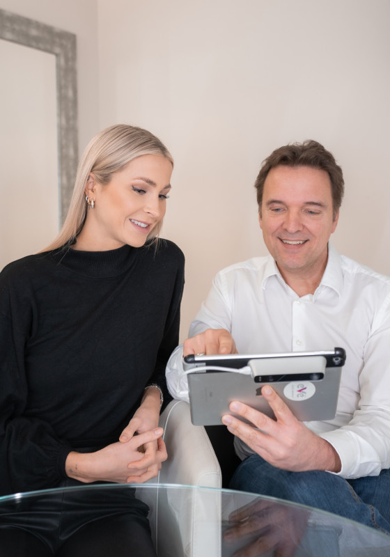 Dr. Christian Döbler berät Patientin und zeigt ihr Bilder auf seinem Tablet