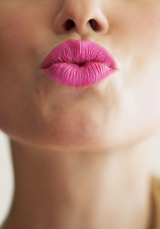 Mund mit pinkem Lippenstift macht Kussmund in Kamera