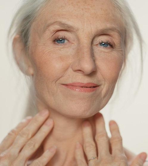 Frau mittleren Alters mit leichten Tränensäcken lächelt