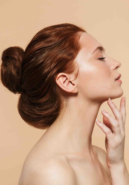 Frau nach Sculptra Behandlung in Düsseldorf, mit gehobenen Kopf und der Hand am Kinn