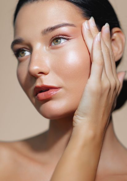 Junge Frau mit glatter, glänzender Haut berührt Gesicht mit Hand